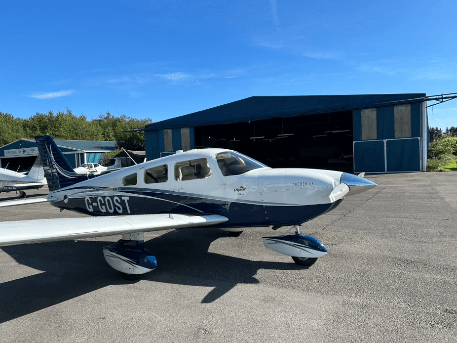 Piper Archer G-GOST side view near hangar